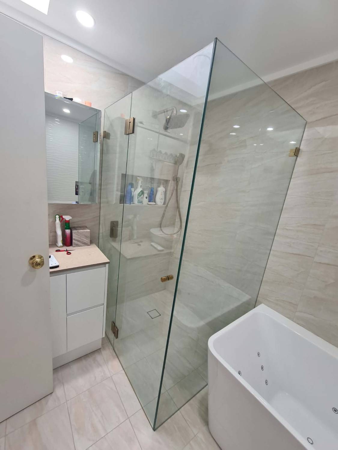 Frameless corner shower screen with brushed brass hinges and handle