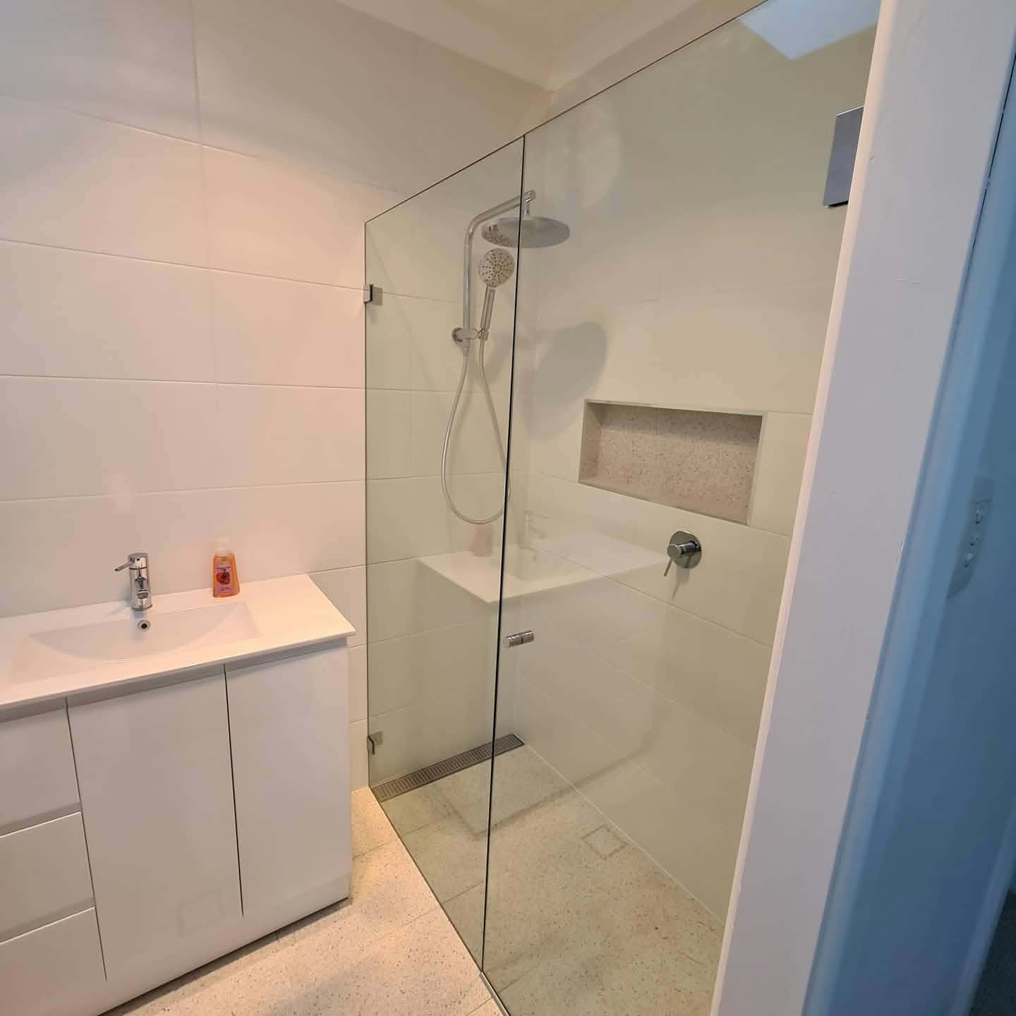 Frameless shower screen with a glass door in a white bathroom