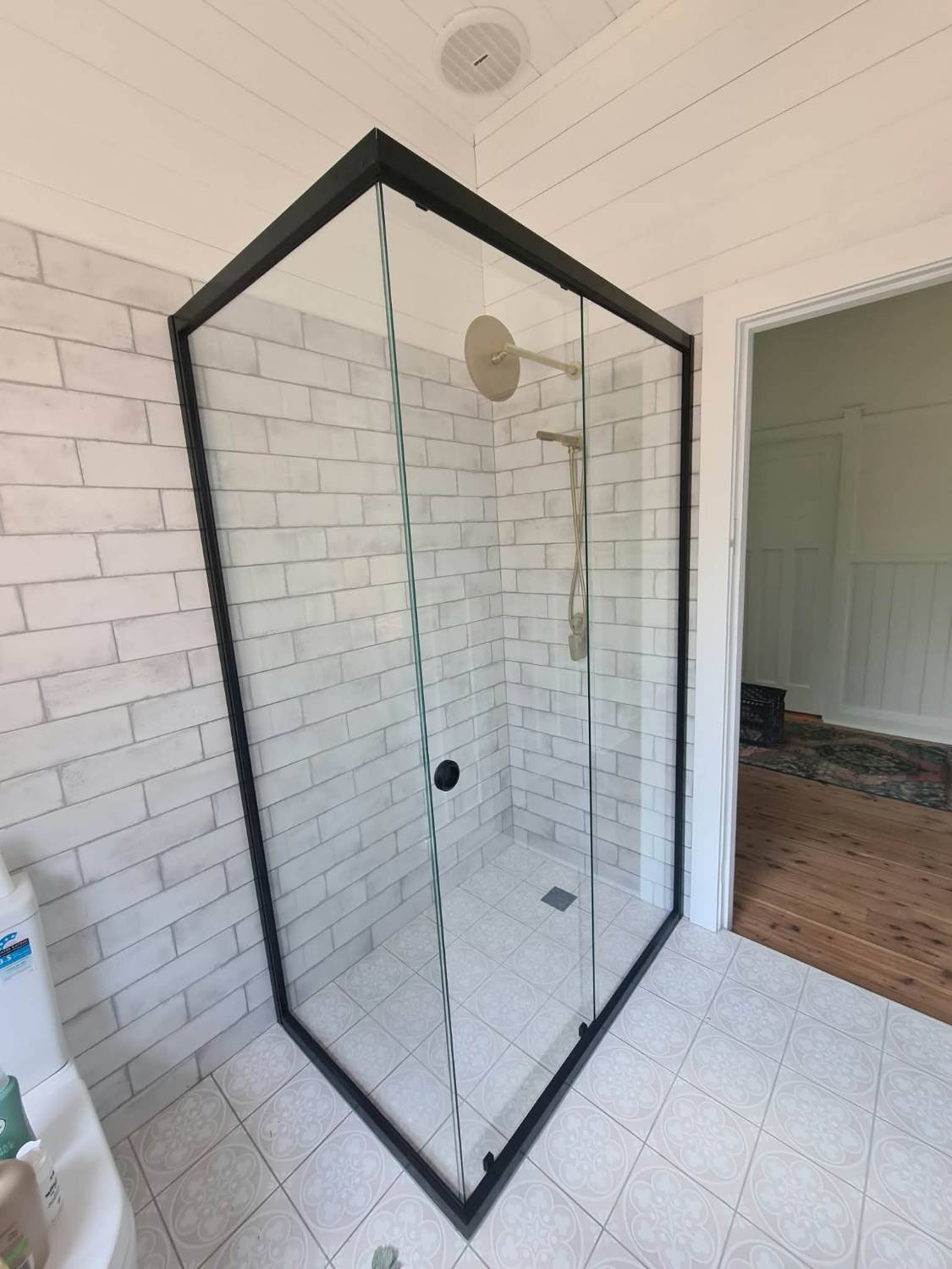 Semi-frameless corner shower screen with a matte black frame and white subway tiles