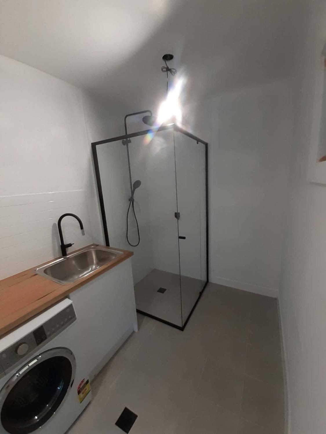 Semi-frameless shower screen with a matte black frame in a laundry